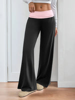 Person wearing black wide-leg pants with a pink waistband indoors.