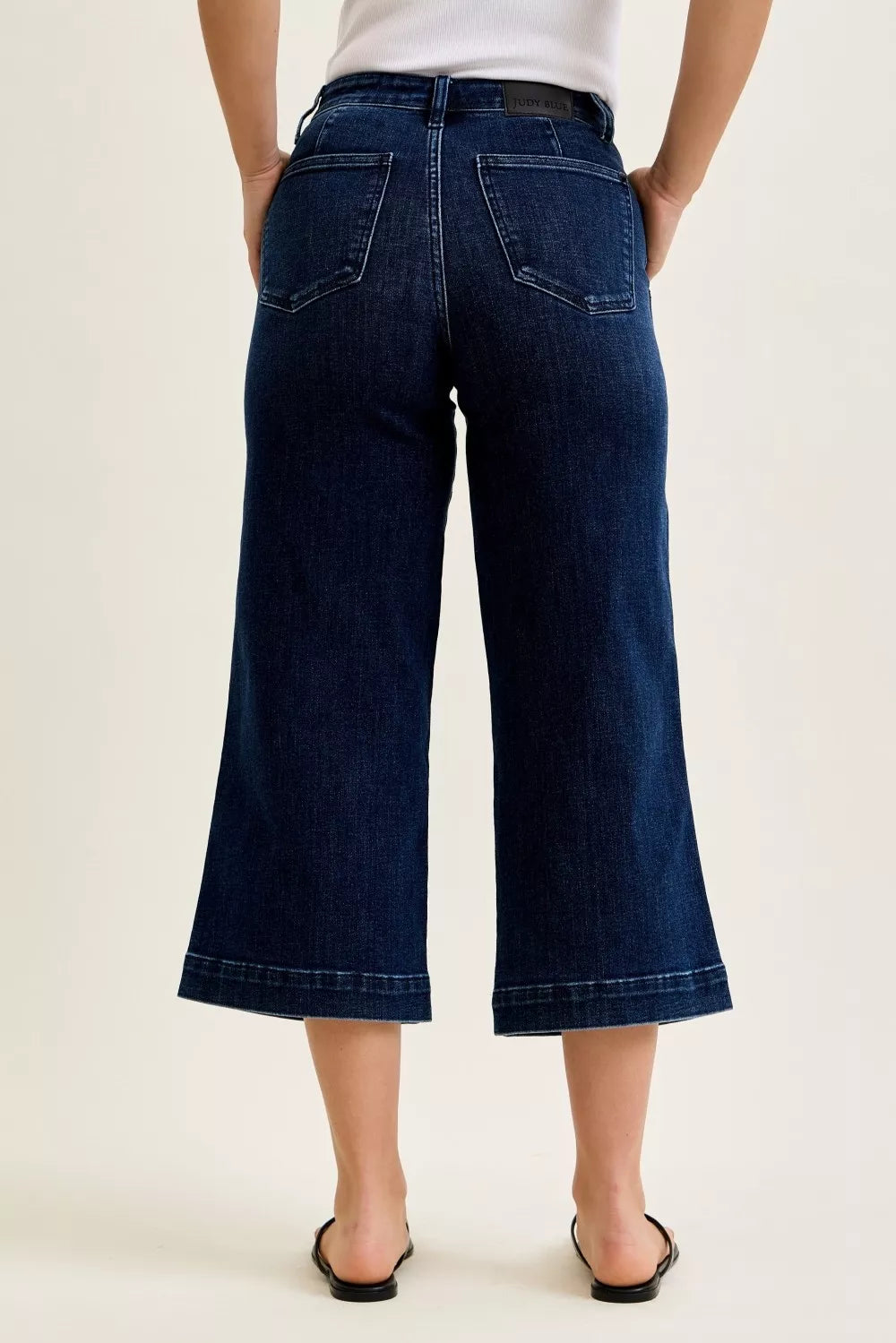 Person wearing dark blue wide-leg jeans on a plain background