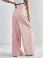 Person wearing light pink wide-leg pants on a white background