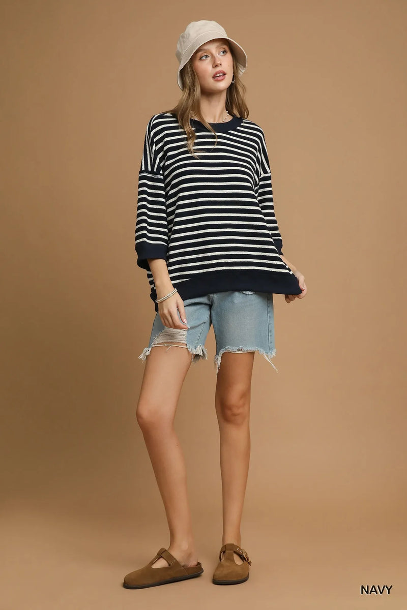 Woman wearing a striped sweater, denim shorts, and a hat on a beige background