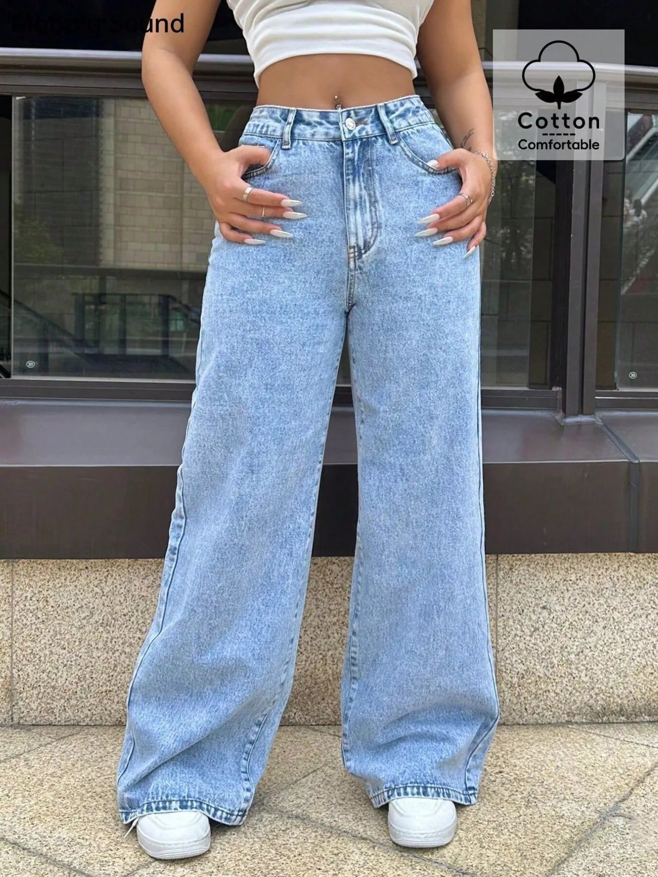Person wearing light blue jeans with a building in the background