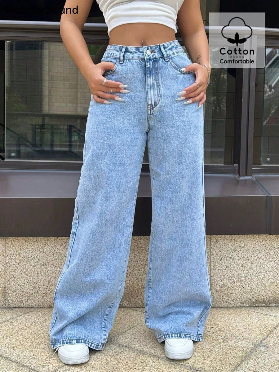 Person wearing light blue jeans with a building in the background