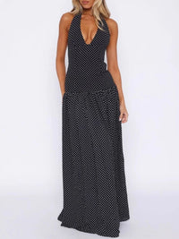 Woman wearing a black polka dot halter neck dress on a white background