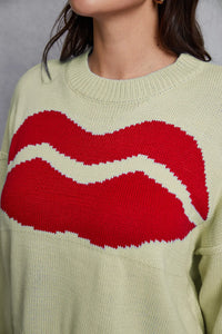 Light green sweater with red and white lips design worn by a person.