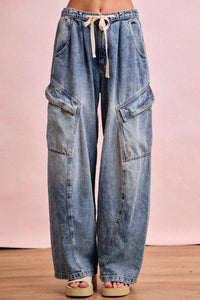 Blue denim cargo pants with a drawstring on a pink background