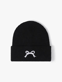 Black beanie with a white bow design on a light gray background