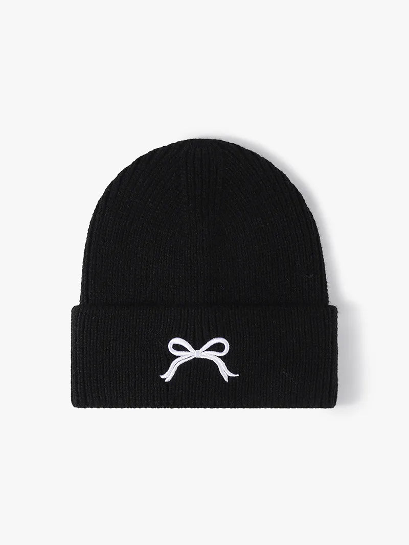 Black beanie with a white bow design on a light gray background