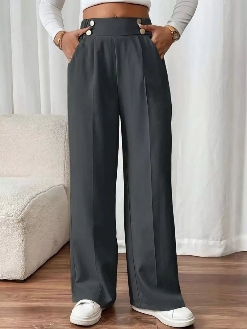 Person wearing gray wide-leg pants with a white background
