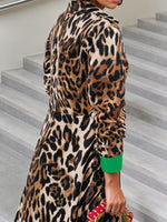 Person wearing a leopard print dress with green cuffs on a staircase