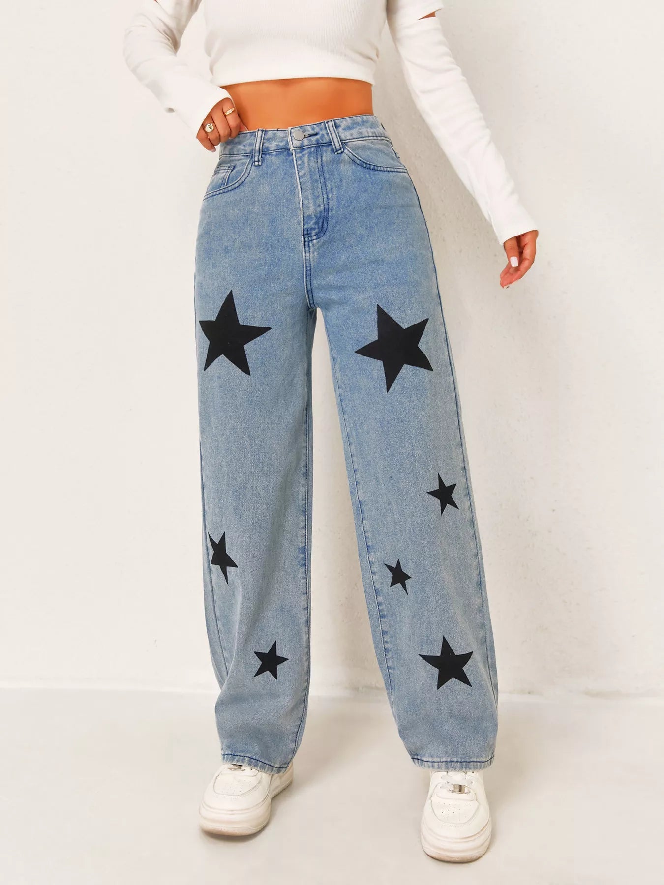 Person wearing blue jeans with black star patterns on a white background
