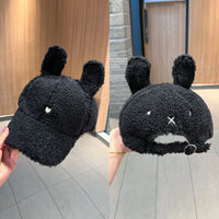 Black plush toy with bunny ears held in front of a mirror.