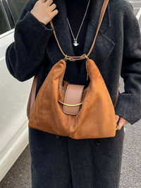 Person wearing a brown leather shoulder bag with a dark coat.
