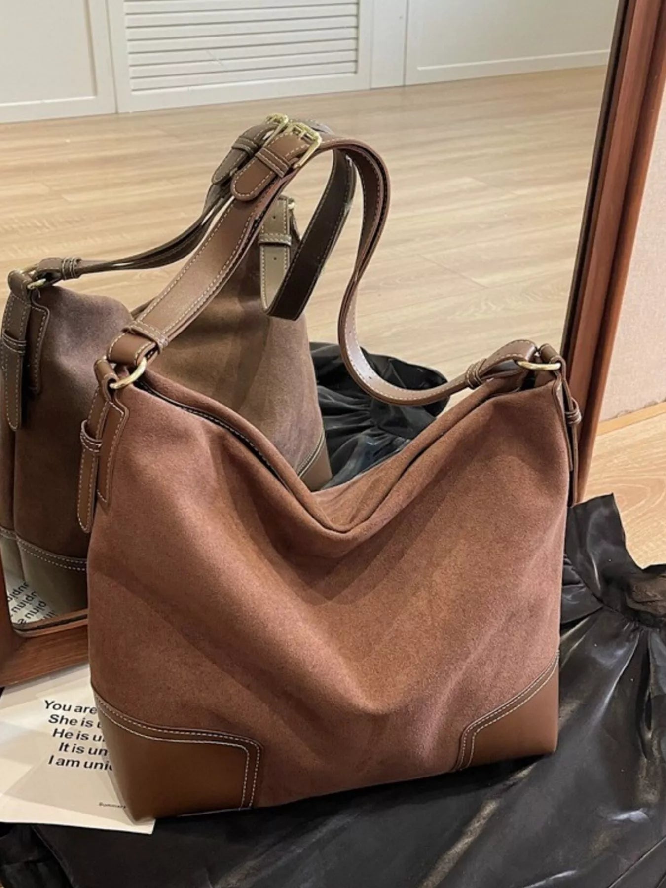 Brown leather handbag on a black surface with a blurred background