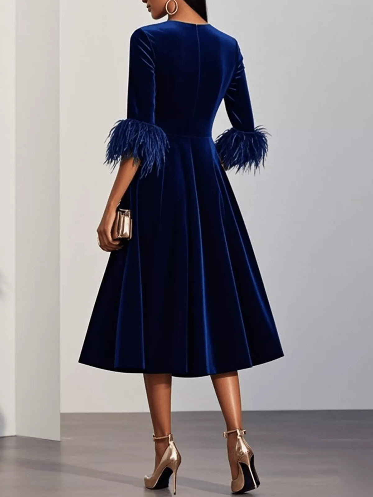 Navy velvet dress with feathered sleeves on a plain background