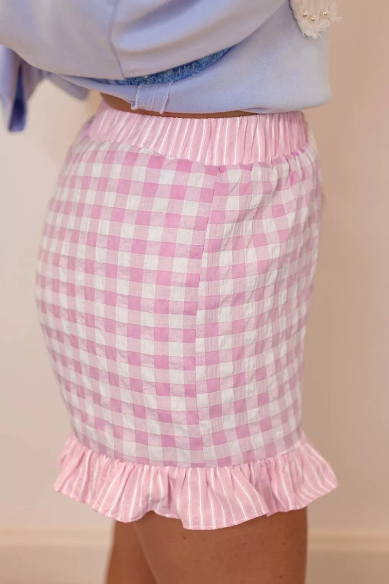 Pink checkered skirt with ruffle hem on a plain background