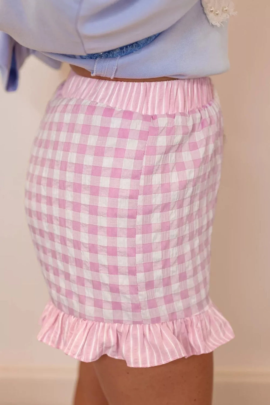 Pink checkered skirt with ruffle hem on a plain background