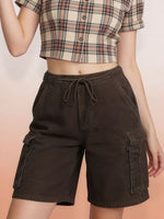 Person wearing brown cargo shorts and a plaid shirt on a peach background
