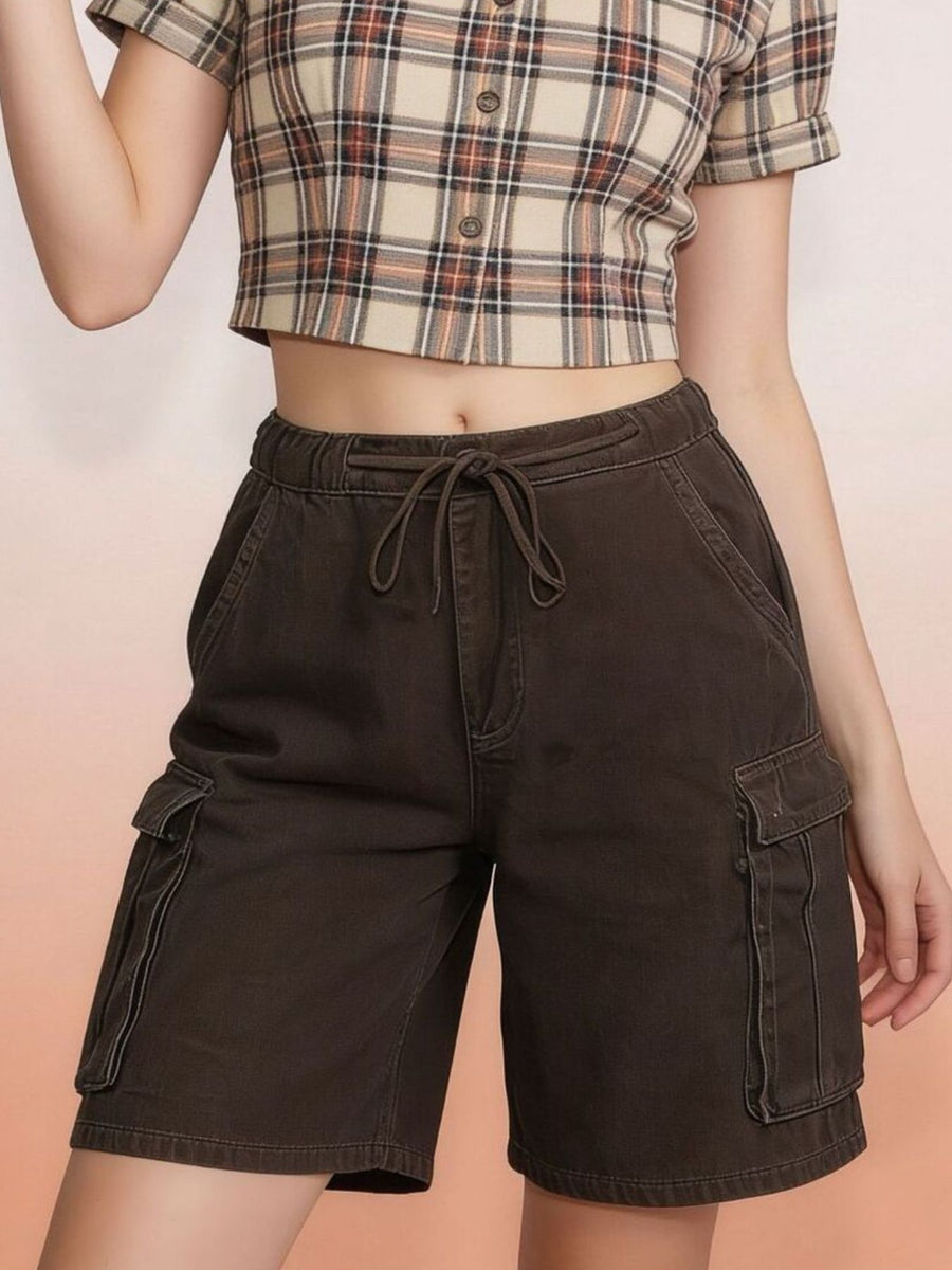 Person wearing brown cargo shorts and a plaid shirt on a peach background