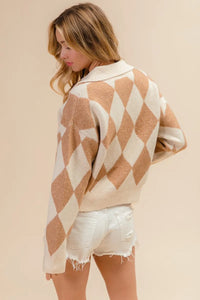 Woman wearing a beige and white diamond patterned sweater with white shorts on a beige background