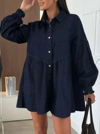 Woman wearing a navy blue button-up shirt dress indoors.