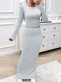 Person wearing a striped long-sleeve top and skirt in a bathroom setting