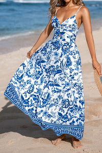 Woman wearing a blue and white floral dress on a beach.