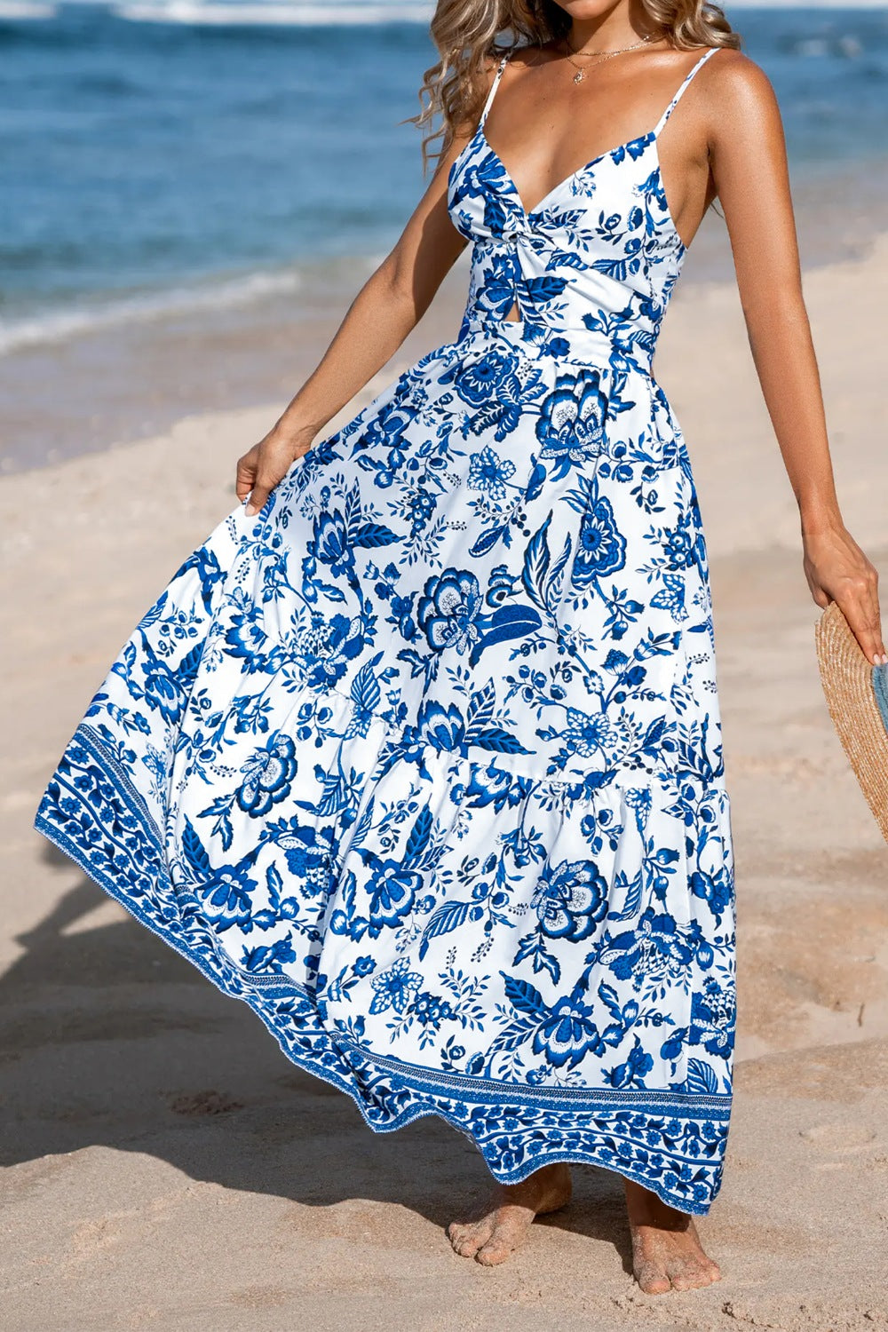 Woman wearing a blue and white floral dress on a beach.