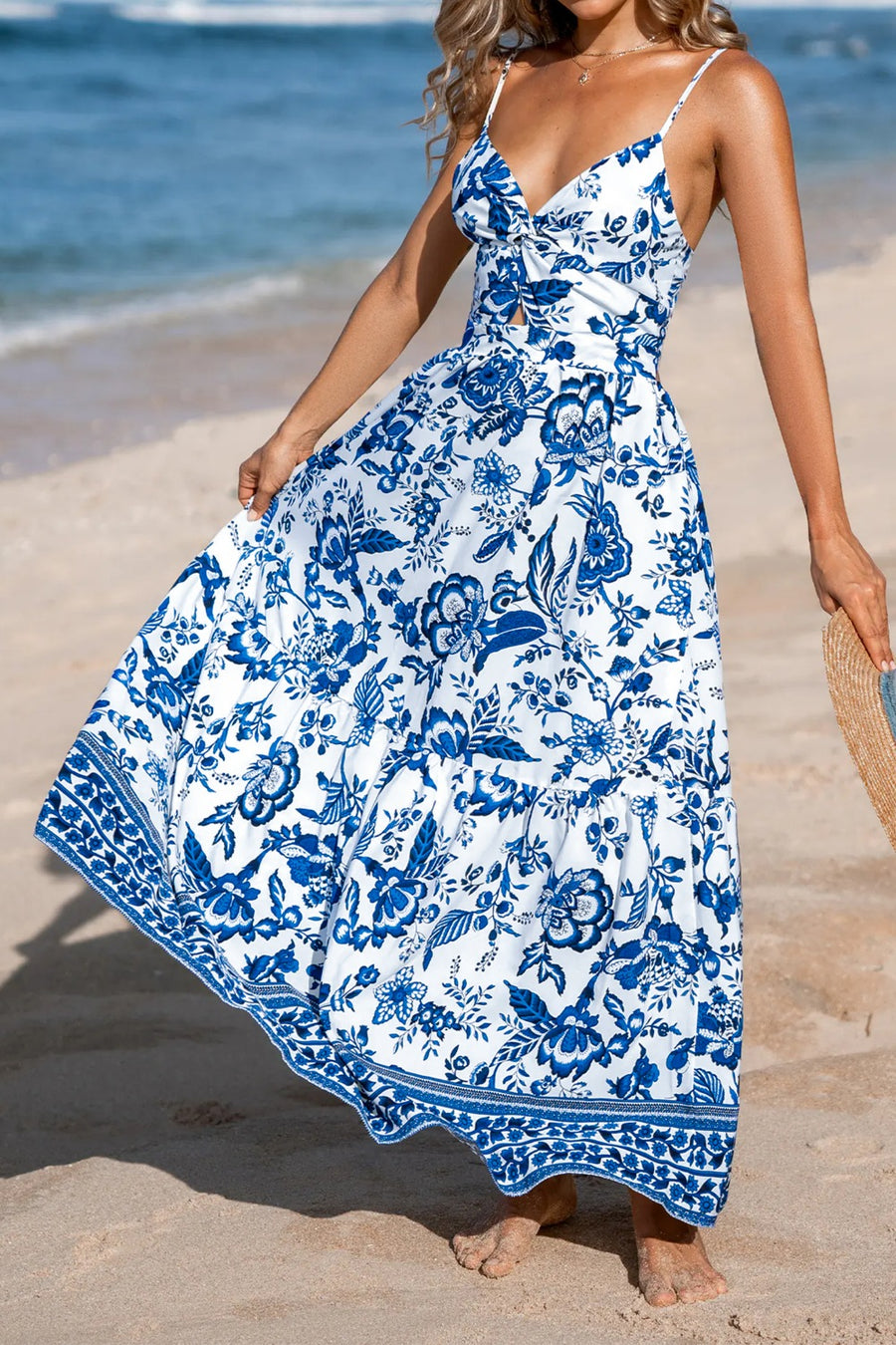 Woman wearing a blue and white floral dress on a beach.