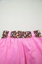 Pink skirt with a leopard print belt on a light gray background