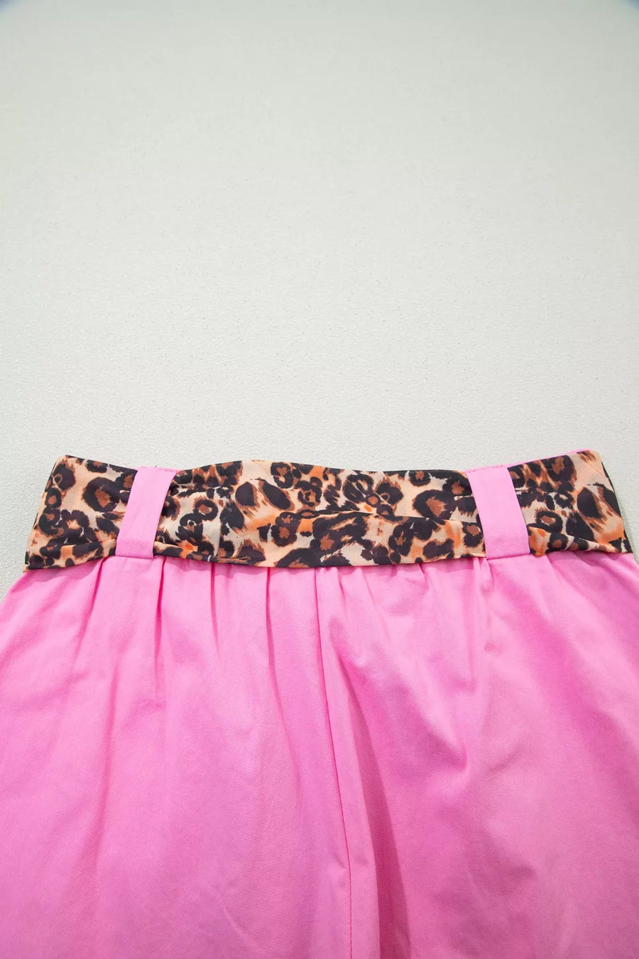 Pink skirt with a leopard print belt on a light gray background