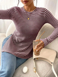 Person wearing a striped sweater holding a drink on a couch