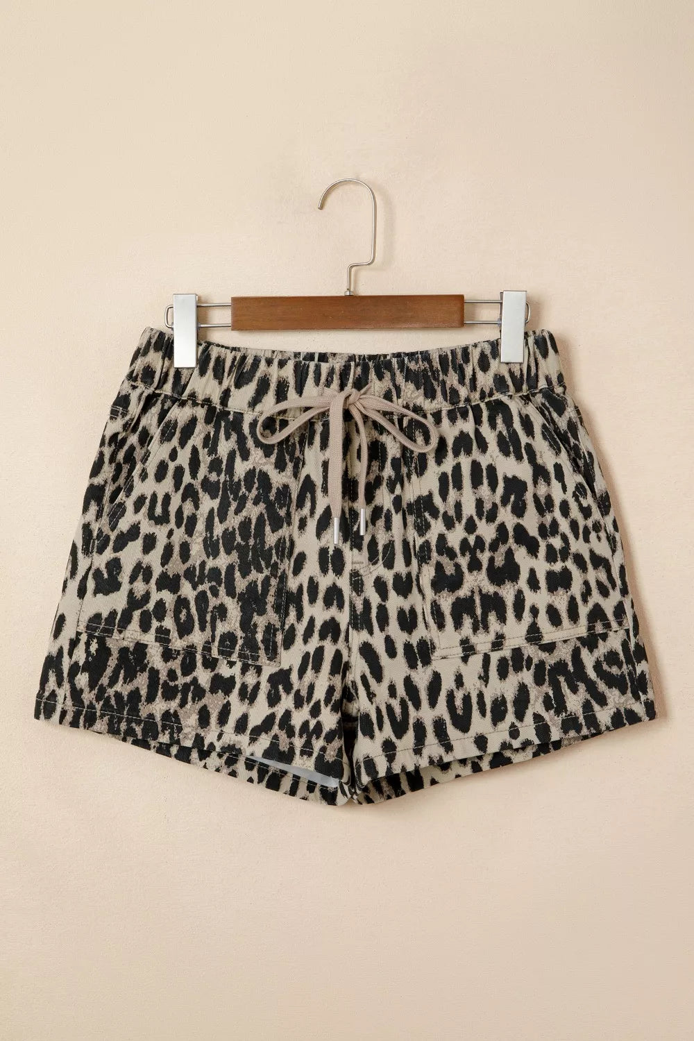 Leopard print shorts on a hanger against a beige background
