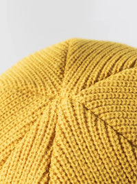 Close-up of a yellow knitted fabric ball on a light gray background
