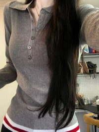 Person wearing a gray ribbed sweater with a blurred background