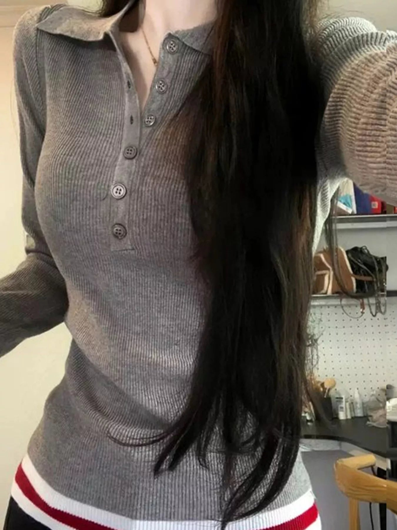 Person wearing a gray ribbed sweater with a blurred background