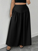 Person wearing a black skirt and black top against a gray background