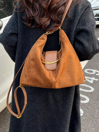 Person wearing a brown leather handbag over their shoulder on a street.
