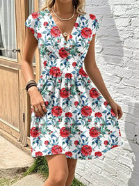 Woman wearing a floral dress with red flowers against a white wall.