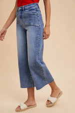 Person wearing blue jeans and white sandals on a beige background