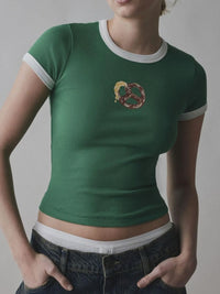 Person wearing a green t-shirt with a pretzel design on a plain background