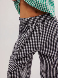 Person wearing black and white checkered pants with a green and white checkered top on a light gray background