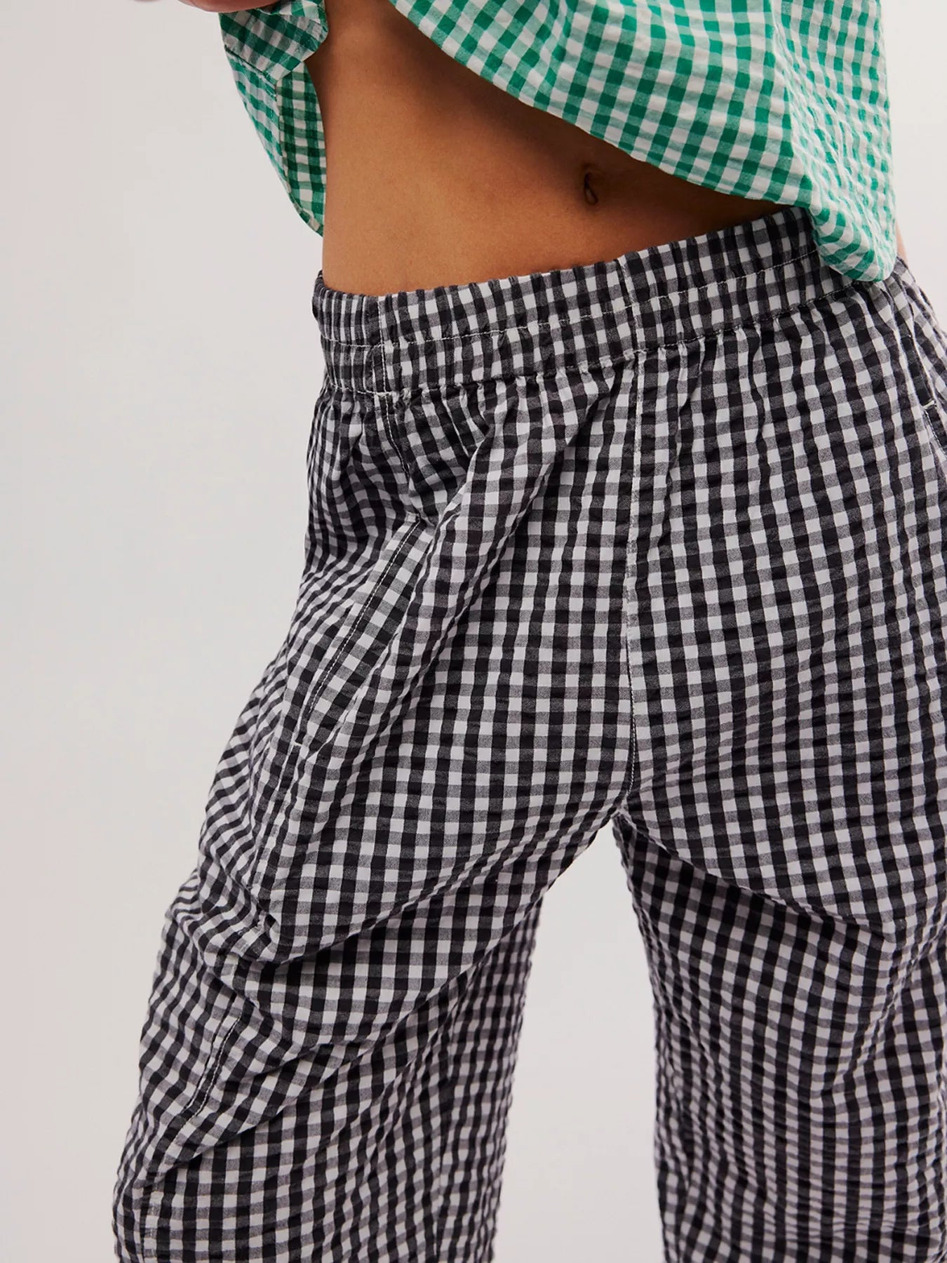 Person wearing black and white checkered pants with a green and white checkered top on a light gray background