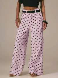 Person wearing pink polka dot pants on a beige background