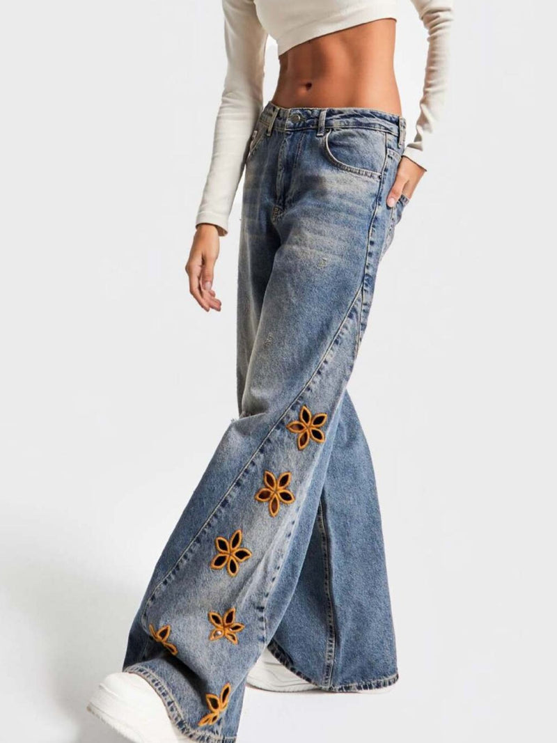 Blue jeans with floral embellishments on a white background