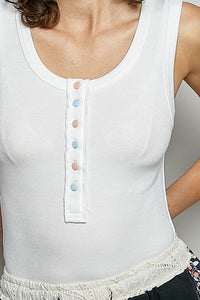 White sleeveless top with colorful buttons worn by a person