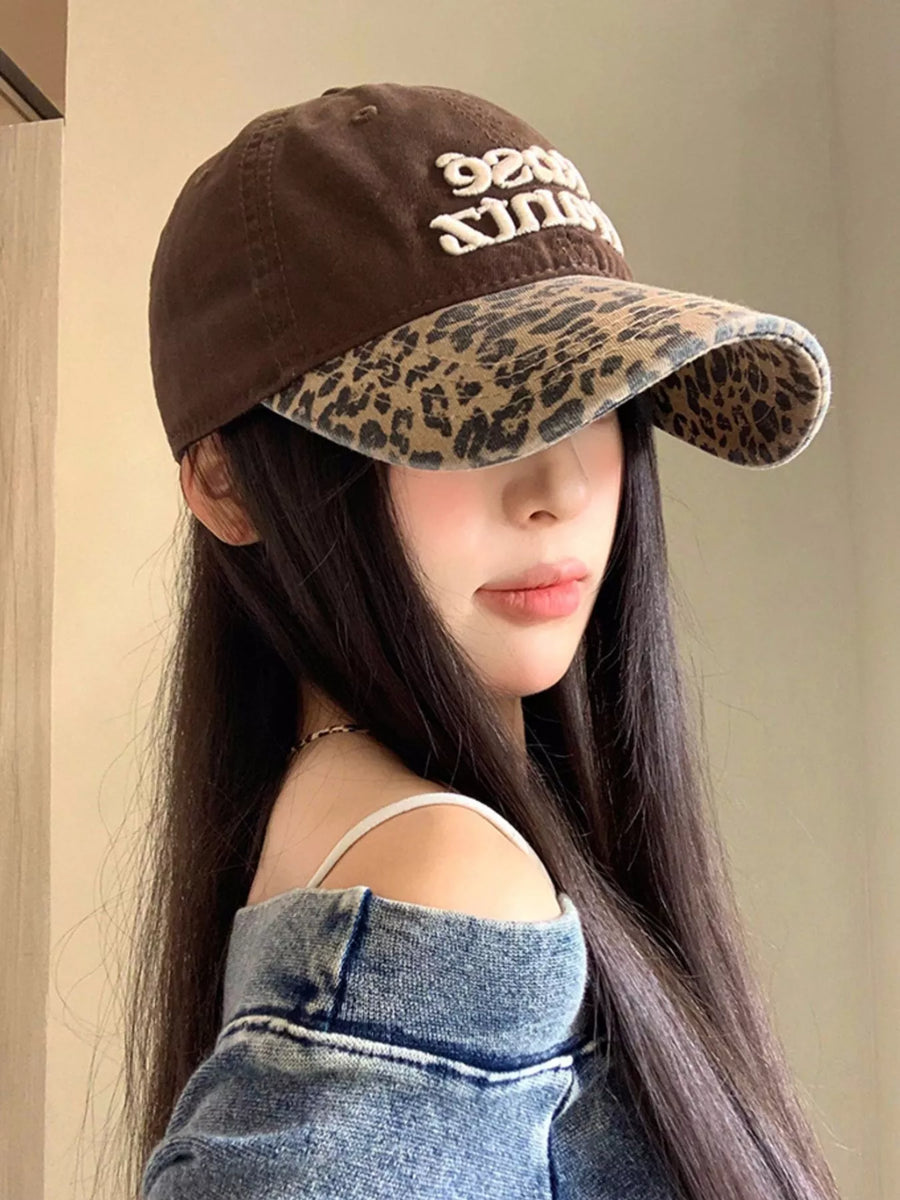 Person wearing a brown cap with leopard print brim and 'Peace Love' text.