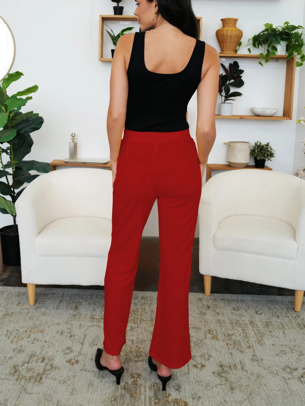 Person wearing a black top and red pants in a living room setting