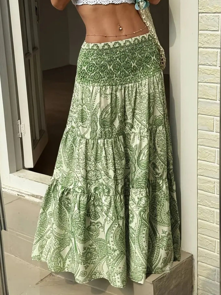Green patterned skirt being held by a person against a neutral background