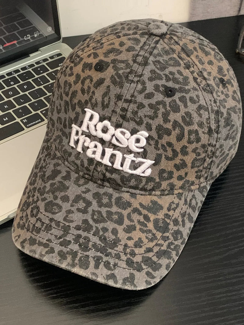 Leopard print cap with 'Rose Frantz' text on a desk with a laptop