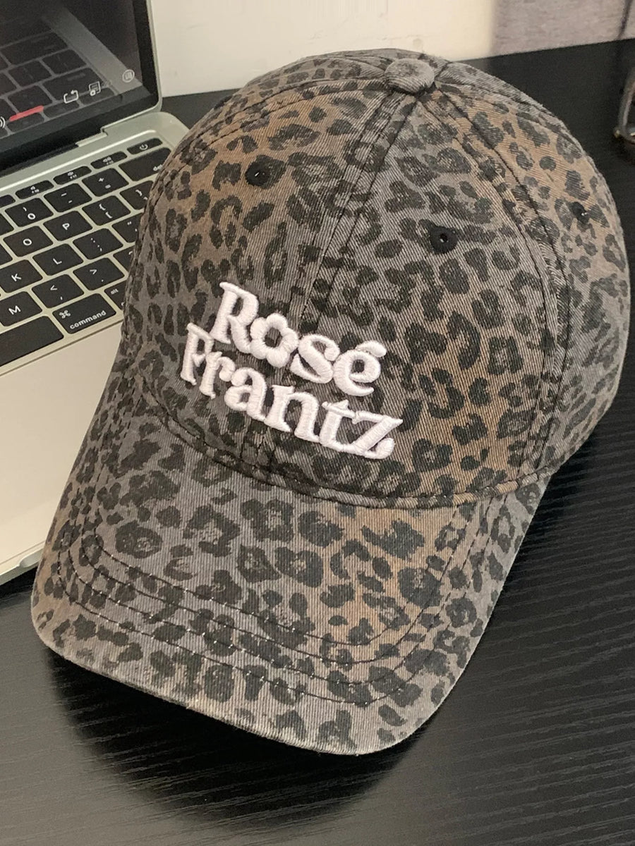 Leopard print cap with 'Rose Frantz' text on a desk with a laptop